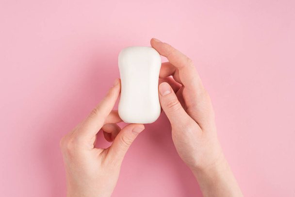 Top above overhead pov first person view photo of female hands holding soap isolated on pastel pink background with copyspace - Fotó, kép