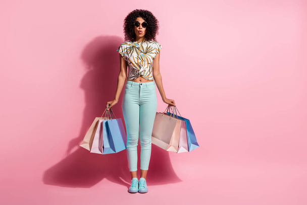Full length body size photo of amazed black skinned woman keeping bags black friday sale isolated on pastel pink color background - Fotografie, Obrázek