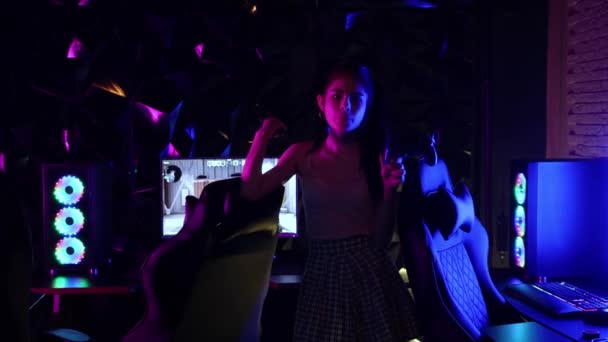 Genç seksi kadın neon oyun kulübünde joystick tutuyor ve sakız üflüyor. - Video, Çekim