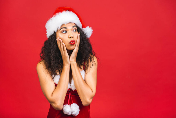 Beautiful smiling happy african american black woman in Santa Claus clothes isolated over red background. New year and christmas concept.  - Фото, изображение