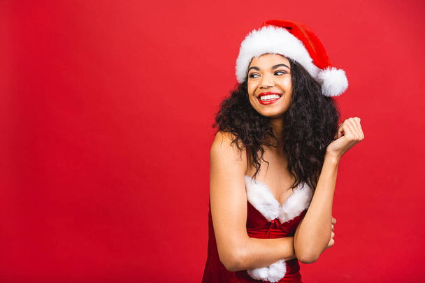 Piękny uśmiech szczęśliwy Afryki czarny kobieta w Santa Claus ubrania izolowane na czerwonym tle. Koncepcja nowego roku i Bożego Narodzenia.  - Zdjęcie, obraz