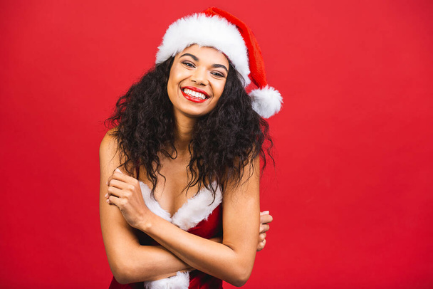 Gyönyörű mosolygós boldog afro-amerikai fekete nő Mikulás ruhák elszigetelt vörös háttér. Új év és karácsony koncepció.  - Fotó, kép