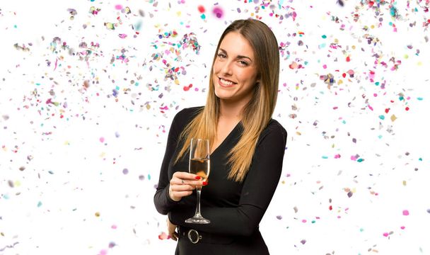 Frau mit Champagner feiert Neujahr und verschränkt die Arme in Seitenlage, während sie mit Konfetti lächelt - Foto, Bild
