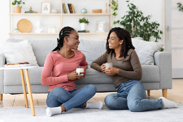 Gülümseyen Afro-Amerikan kankaları kahve içerken sohbet ediyorlar. - Fotoğraf, Görsel