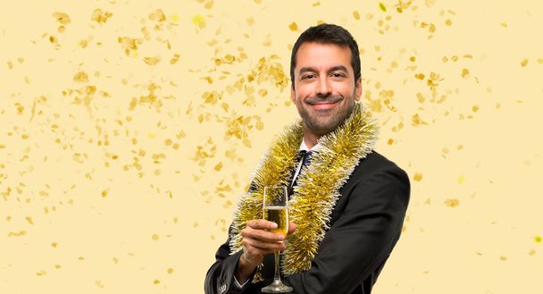 Человек с шампанским, празднующий Новый год держит руки скрещенными в боковом положении, улыбаясь конфетти на вечеринке - Фото, изображение