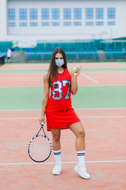Porträt einer Tennisspielerin, die Ball mit Schutzmasken draußen hält - Foto, Bild