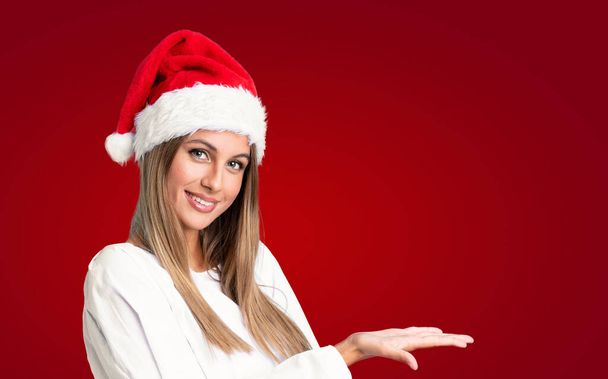 Lány karácsonyi kalap felett elszigetelt háttér kiterjeszti kezét oldalra meghívó jönni - Fotó, kép