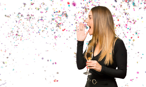 Şampanyalı bir kadın yeni yılı kutluyor. Yan tarafa bağırıyor ve konfetiyle bir şey duyuruyor. - Fotoğraf, Görsel