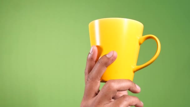 kéz gazdaság sárga kávé bögre újra zöld háttér  - Felvétel, videó