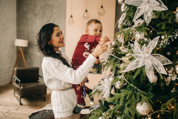 Szczęśliwa matka z synem spojrzeć na dekoracje świąteczne w pobliżu choinki. - Zdjęcie, obraz