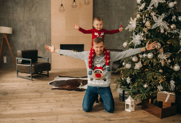Feliz padre con su hijo jugar y divertirse cerca del árbol de Navidad con decoraciones. - Foto, imagen