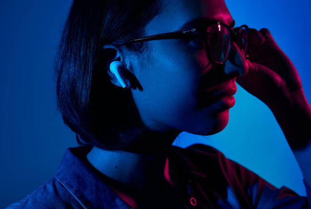Woman adjusting glasses and listening to music - Foto, imagen