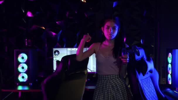 Молодая привлекательная женщина держит джойстик в неоновом игровом клубе и взрывает жвачку - Кадры, видео
