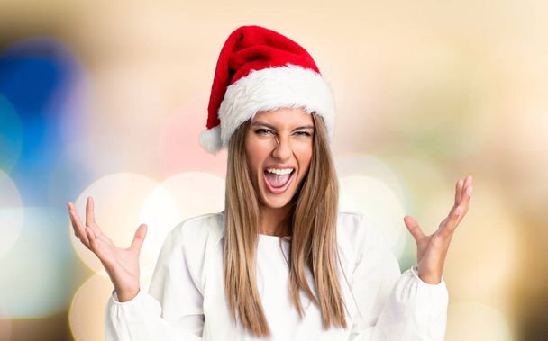 Dívka s vánoční klobouk nešťastný a frustrovaný s něčím přes nesoustředěné pozadí - Fotografie, Obrázek