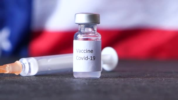 Κοντινό πλάνο του εμβολίου coronavirus και της σύριγγας o αμερικανική σημαία  - Πλάνα, βίντεο