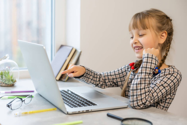 Kleines Mädchen macht ihre Hausaufgaben zu Hause und benutzt einen Laptop - Foto, Bild