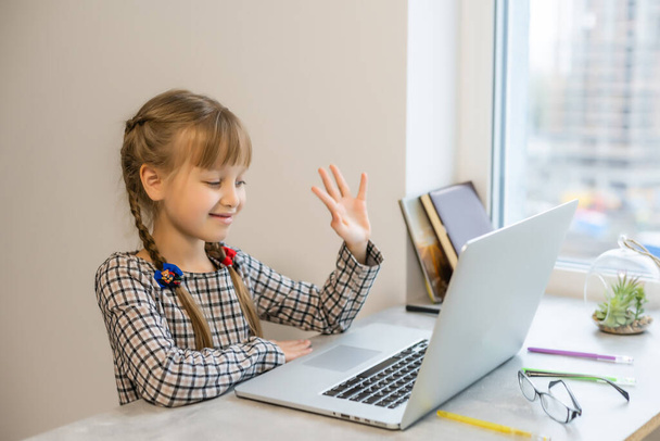 Küçük kız ödevini evde yapıyor ve dizüstü bilgisayar kullanıyor. - Fotoğraf, Görsel