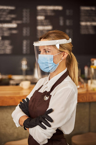 Привлекательная официантка, работающая в карантине в медицинской маске - Фото, изображение