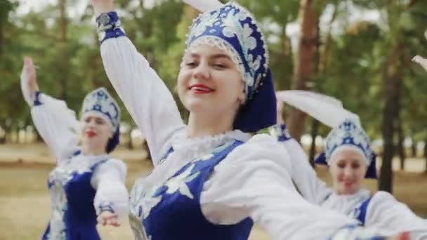 Крупный план молодых красивых женщин в голубых русских традиционных народных костюмах танцуют в летнем лесу - Кадры, видео
