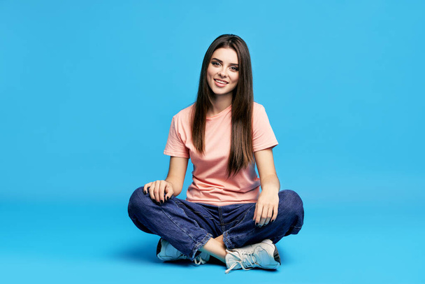 Pretty beautiful young woman posing on studio sitting on the floor - Фото, зображення