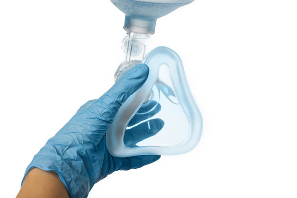 Femme médecin de la main en gants bleus tient un sac de am-bu pour la ventilation artificielle des poumons et met sur le patient vue à la première personne (vue du patient) isolé sur fond blanc - Photo, image