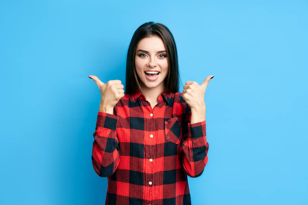 Happy smiling hipster woman showing thumbs up on blue background - Φωτογραφία, εικόνα