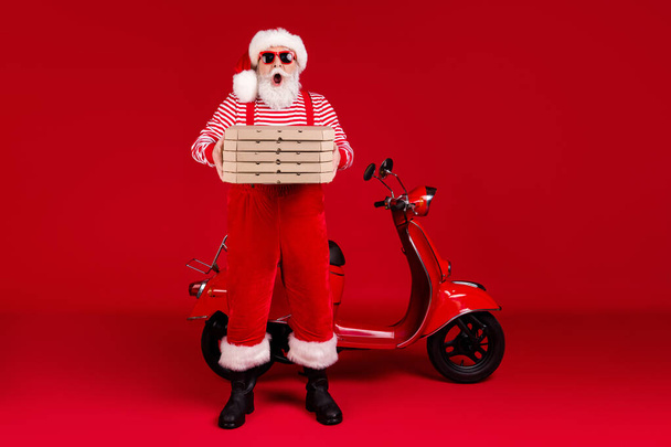 Full length photo of pensioner grandpa moped hold pizza boxes open mouth late omg wear santa x-mas costume suspenders sunglass boots striped shirt cap isolated red color background - Fotografie, Obrázek