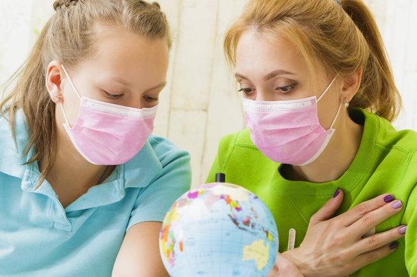 Семья в медицинских масках обнимает глобус - Фото, изображение