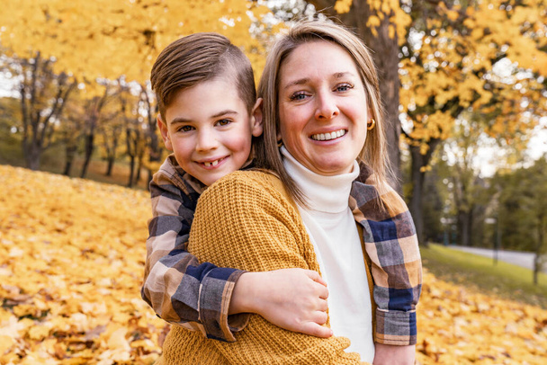 Happy family mother and child boy in the autumn leaf fall in park - Photo, Image