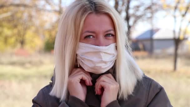 dziewczyna w masce medycznej na ulicy jesienią na Ukrainie w słońcu spacery po mieście - Materiał filmowy, wideo