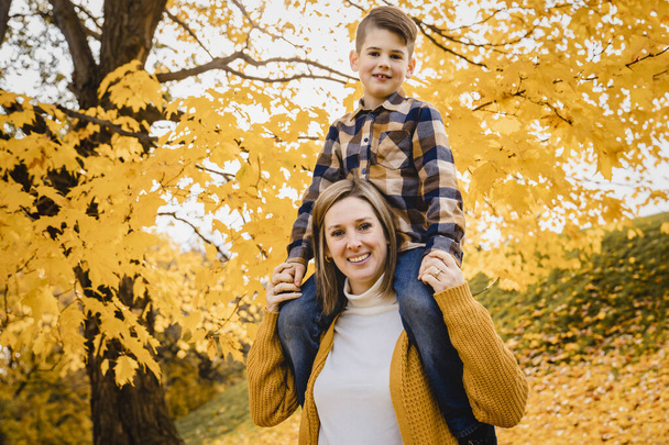 Happy family mother and child boy in the autumn leaf fall in park kid on the shoulder - Foto, Imagem