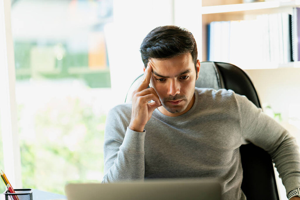 Um homem que trabalha com um laptop em um escritório em casa Pessoas de negócios são estressadas pelo trabalho. - Foto, Imagem