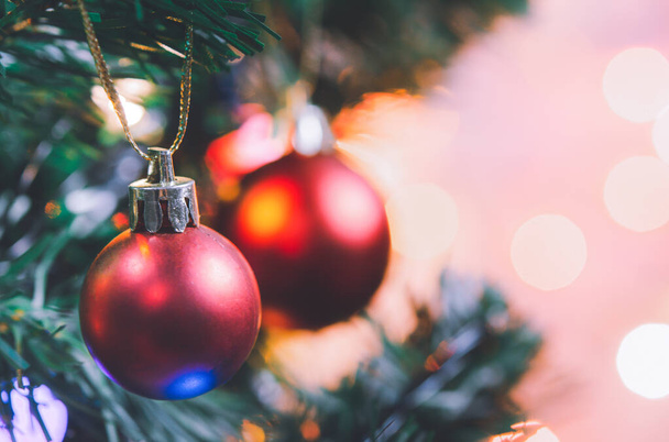 Karácsonyi dekoráció. Piros golyó lóg fenyő ágak karácsonyfa koszorú és díszek felett elvont bokeh háttér másolás spac - Fotó, kép