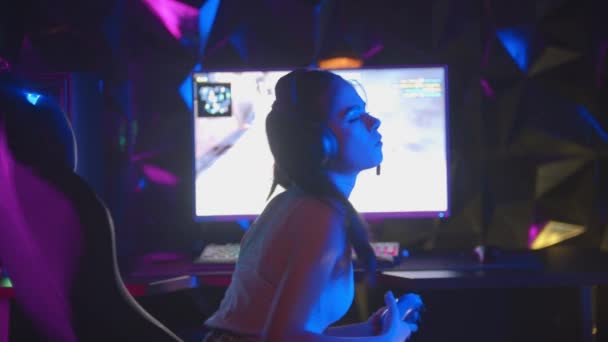 Mujer joven jugando un juego en el club de juego - se da la vuelta y saludando con un joystick - Metraje, vídeo