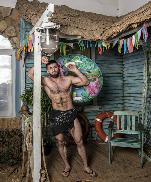 bonito fisicamente bem desenvolvido homem no alpendre de uma casa de pesca perto do mar - Foto, Imagem