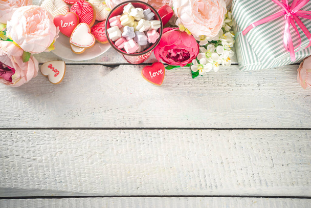 Valentijnsdag achtergrond met teder roze rood wit pioenroos bloemen en hart gevormd Valentijnsdag decoratie, houten witte achtergrond kopieer ruimte  - Foto, afbeelding