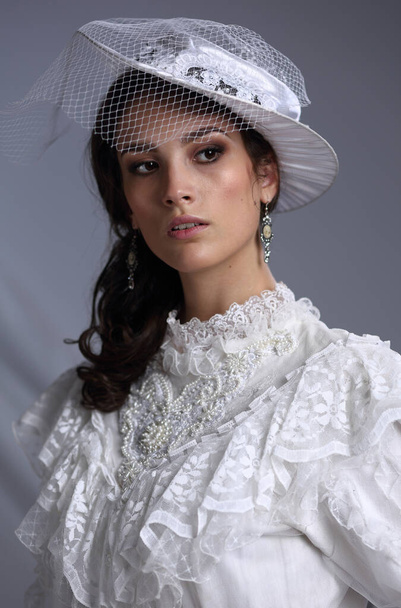 Studio portrait of a beautiful girl in a hat with a veil in retro style - Foto, Imagen