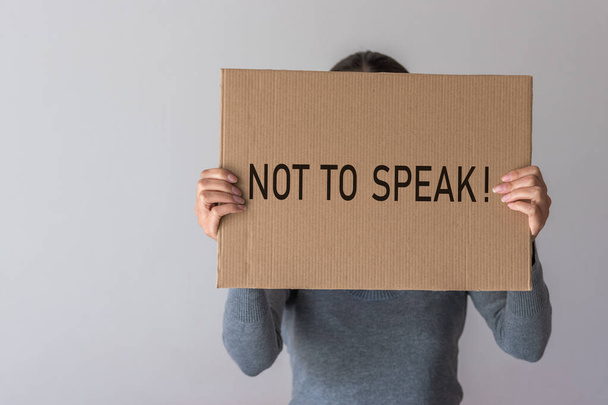 A woman holds a banner with the inscription NOT TO SPEAK in front of her. - Foto, Imagem