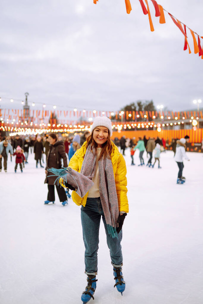 Beautiful woman have fun, active ice skating on the ice arena in the city square in winter on Christmas Eve. Winter holidays concept. Lights around. - Фото, зображення