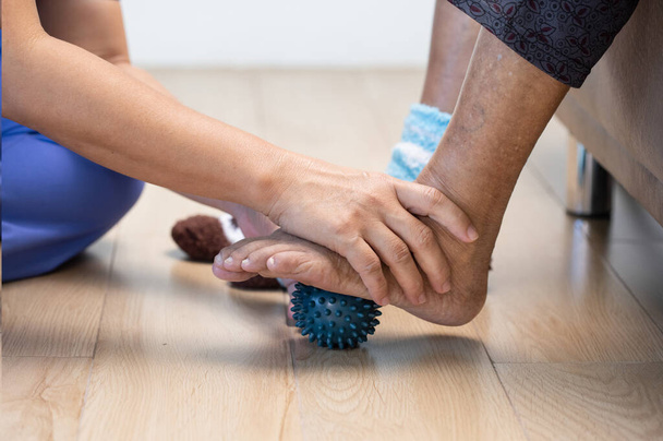介護者と運動指、手のひら、手と足の筋肉のためのゴムボールを行う高齢女性が世話をする. - 写真・画像
