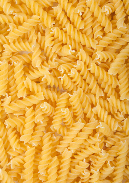 Raw homemade yellow fusilli pasta as texture background. Top view - Foto, afbeelding