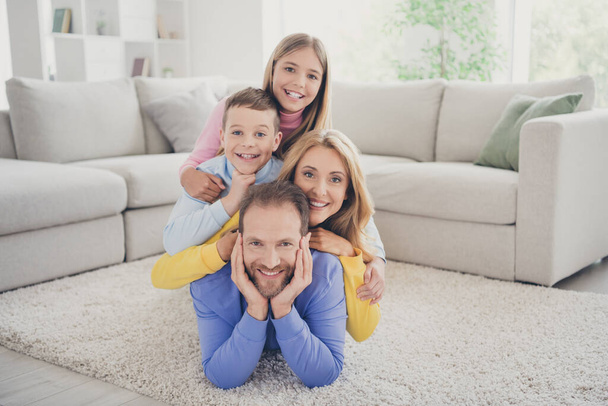 Full size photo of idyllic family mommy and two kids boy girl lying on daddy carpet in house indoors - Фото, изображение