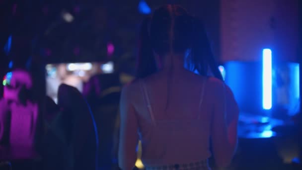 Молодая привлекательная женщина с хвостиком гуляет в игорном клубе - стоя у стула и держа в руках джойстик - Кадры, видео