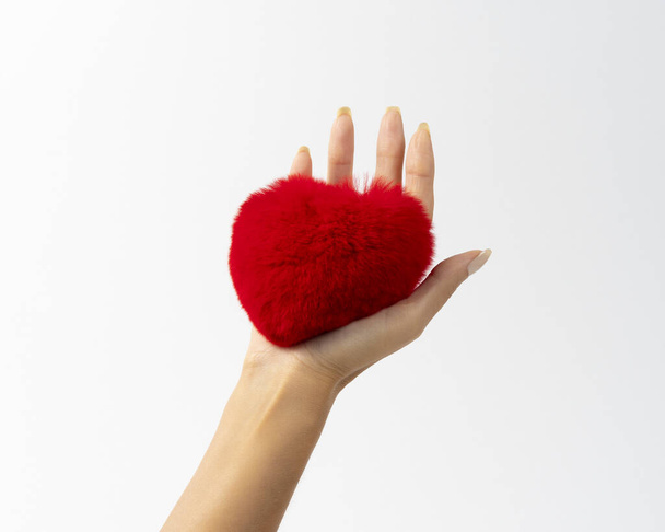 Heart shape red fluffy fur toy in woman hand. Minimal Valentine's day or Love concept. - Foto, imagen