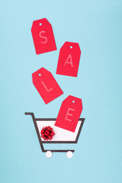 Super Sale day or Singles day concept. Shopping trolley and red tags on blue paper background. Online shopping of China. Top view, flat lay, copy space. - Photo, Image