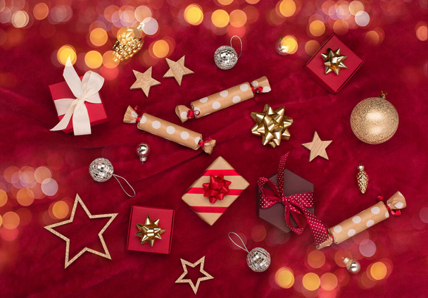 Noël vacances hiver Nouvel An carte de fête. Décorations en bois d'or de Noël, coffrets cadeaux, cannes de bonbons sur fond textile rouge. Pose plate, vue du dessus, espace de copie - Photo, image
