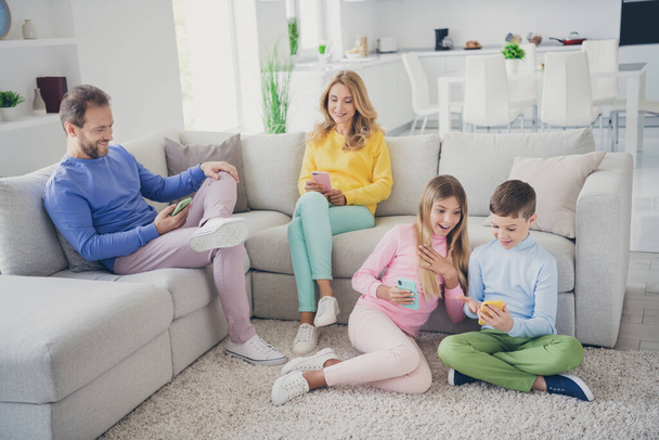 Full size photo of family people mom dad two small kids sit floor sofa read social network shocked news in house indoors - Foto, Bild