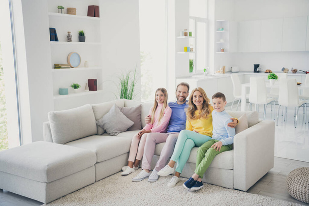 Full body photo of positive family mom dad two kids boy girl hug sit couch in living room house indoors - Фото, зображення