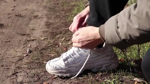 girl tie shoelaces on sneakers on the road in the autumn afternoon in the sun - Footage, Video