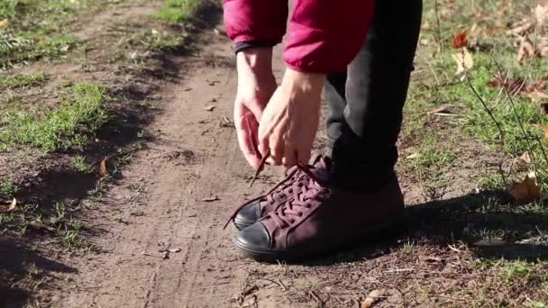girl tie shoelaces on sneakers on the road in the autumn afternoon in the sun - Footage, Video